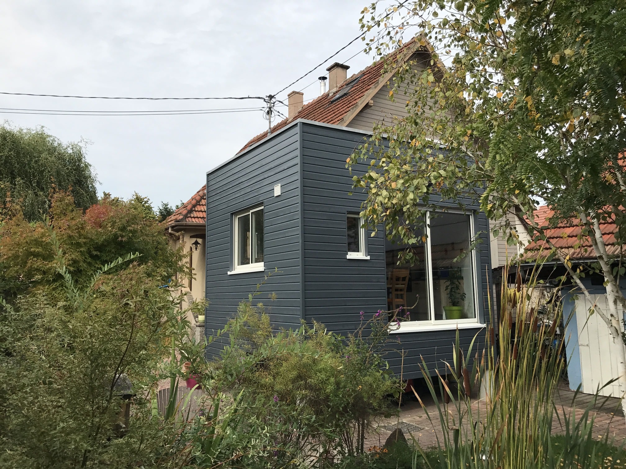 Une maison avec une extension moderne signée Pouss'murs, parfaitement intégrée à l’architecture d’origine.